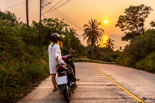 Voyageur en scooter sur une route tropicale en Thaïlande